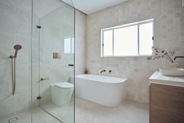 Luxury shower featuring a frameless glass screen and brushed bronze shower fittings in a Newtown bathroom.