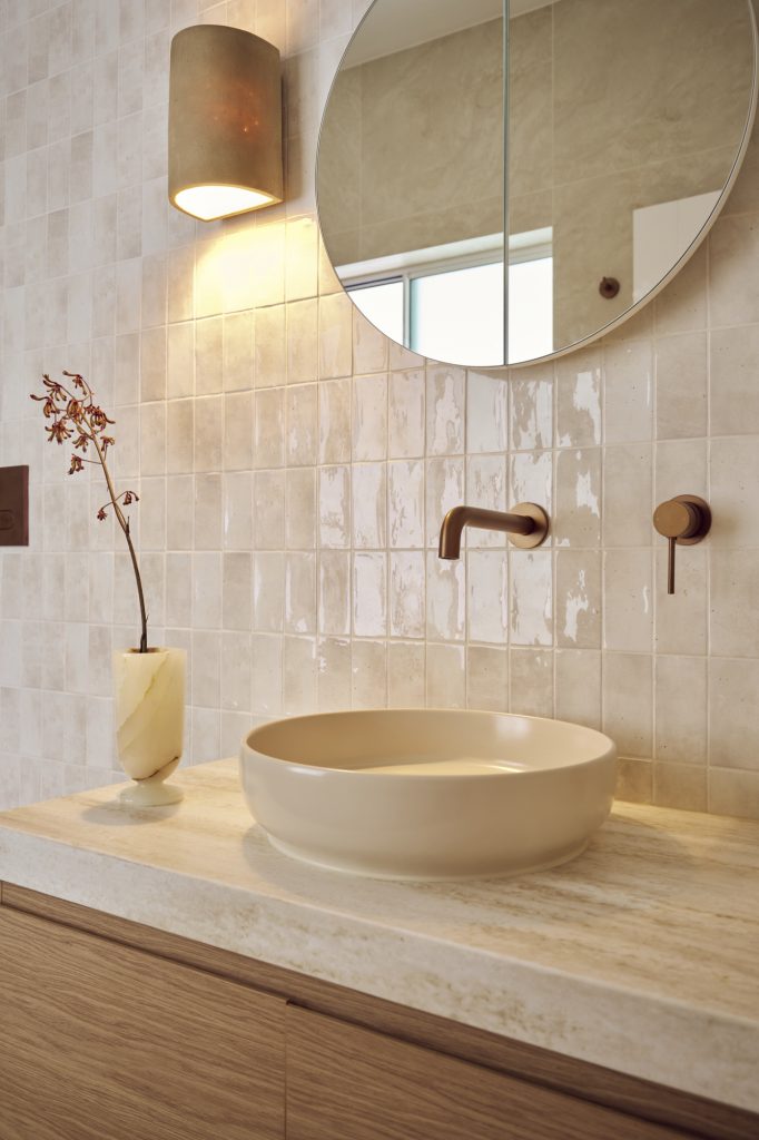 Sconce wall light with a timber vanity with wall-mounted mixers in brushed bronze